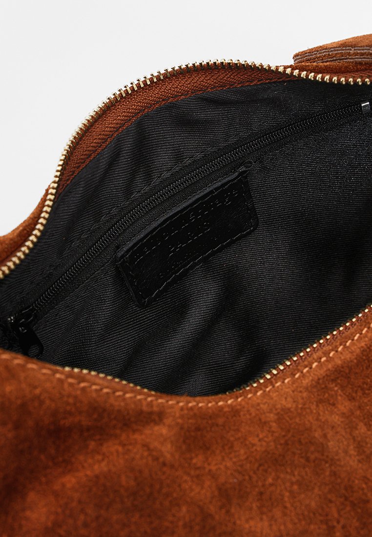 Braune Wildledertasche mit einem schwarzen Stoffinnenraum. Ausgestattet mit einem goldenen Reißverschluss und einem kleinen Reißverschlussfach im Inneren. Etikett im Fach sichtbar.