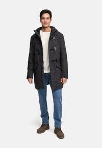 Dark gray wool duffle coat with toggle fastenings and a hood, paired with a light sweater and blue jeans. Brown shoes complete the outfit.