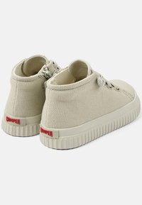 Sneaker alte beige realizzate in tela testurizzata con suola in gomma e logo rosso "Camper" sul tallone, dotate di chiusura con lacci.