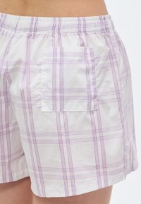 Βαμβακερά σορτς καρό σε λευκό με ροζ και λεβαντίνι λεπτομέρειες. Ελαστική μέση και τετράγωνη πίσω τσέπη. Μαλακή υφή, άνετη γραμμή.