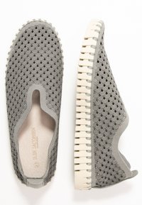 Scarpe slip-on grigie con un motivo testurizzato a onde. Suola in gomma flessibile con dettagli scallop in un colore chiaro a contrasto.