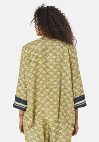 Kimono giallo con motivo floreale in bianco e blu navy, con polsini a righe blu navy. Tessuto morbido con una vestibilità comoda.