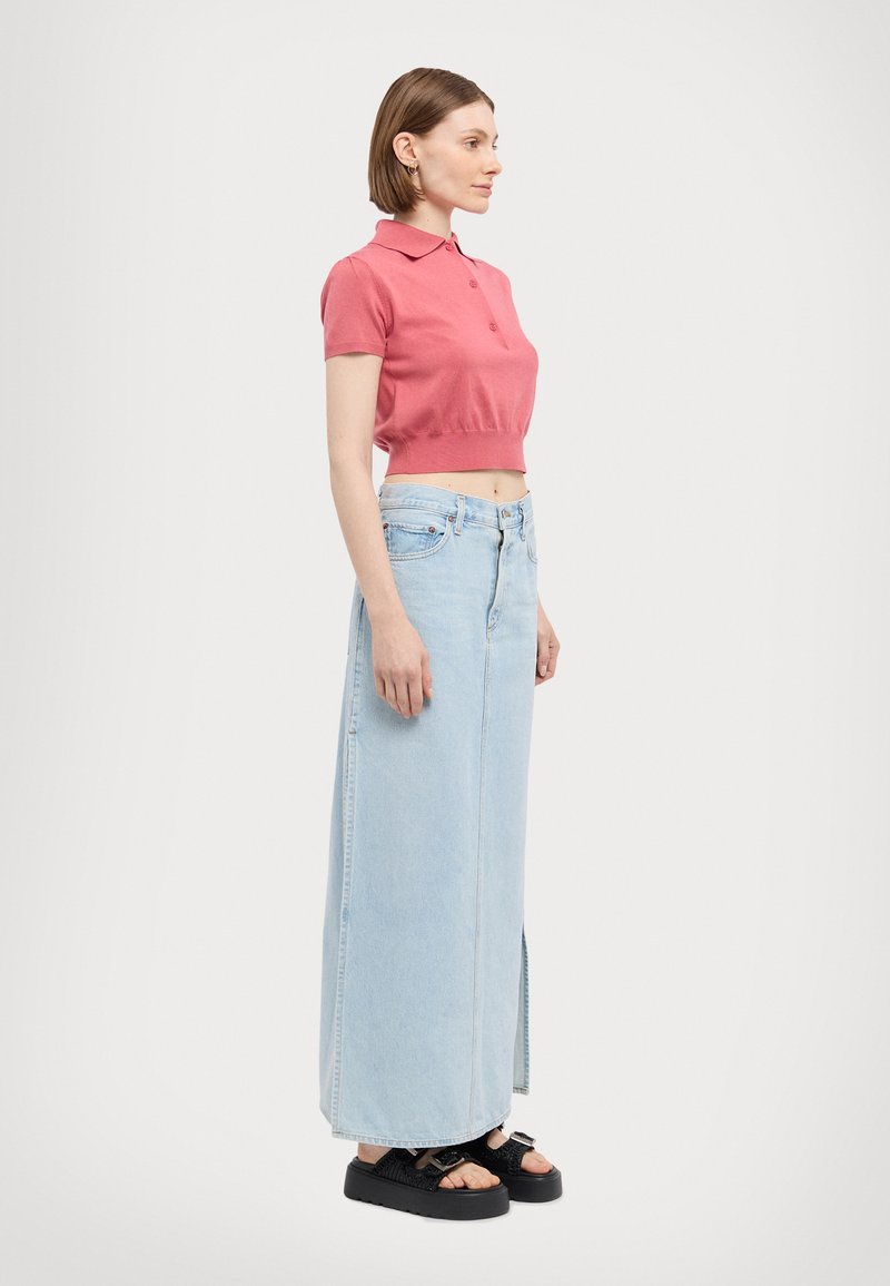 Lys rosa kortermet polo skjorte, kombinert med en lys blå denim maxiskjørt med sidespalter og svarte platå sandaler.