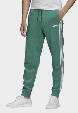 Pantalones deportivos verdes hechos de tela suave, con rayas laterales blancas y una cinturilla ajustable con cordón. Detallados con un logo en la cadera izquierda.