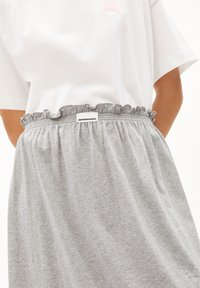 Gray skirt with a ruffled waistband, featuring an elastic band and a small label reading "ARMEDANGELS." Soft fabric texture and casual design.