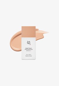 Daily Tinted Fluid Sunscreen i en rektangulær hvit flaske med beige kork; ledsaget av en prøve av tonet solkrem.