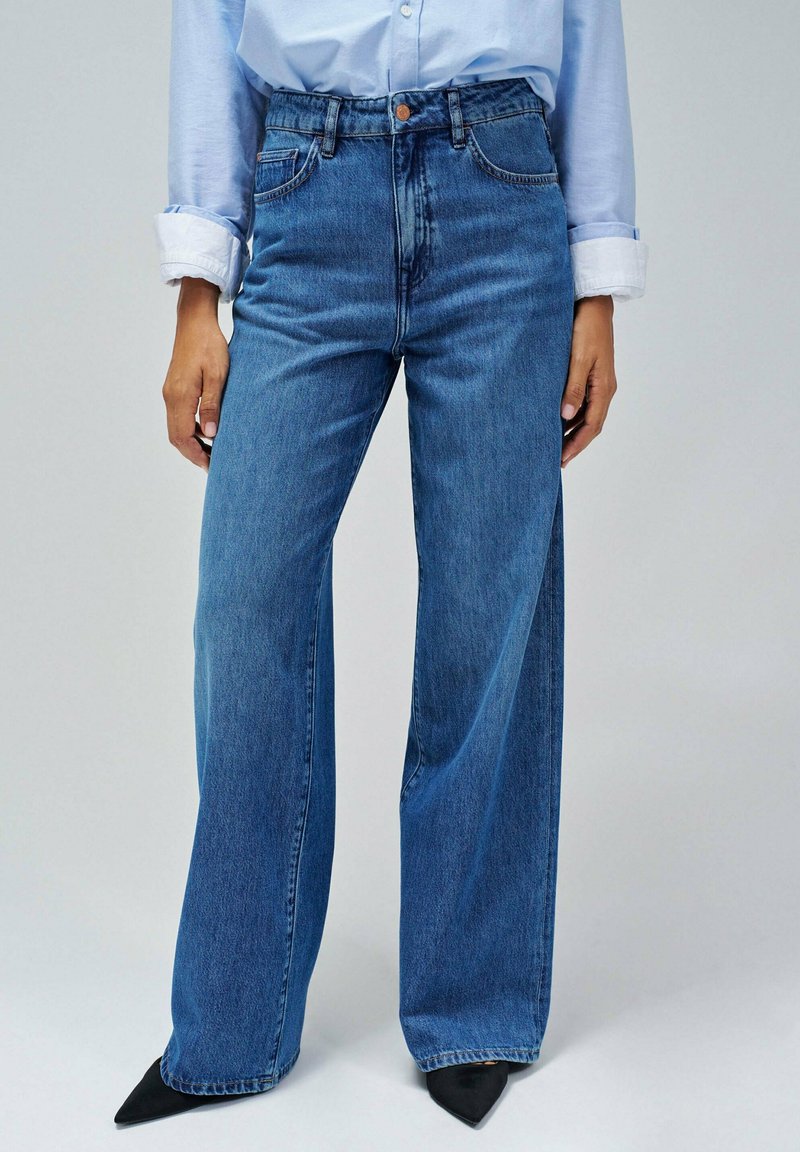 Lichtblauwe high-waisted jeans met een wijduitlopende snit, gemaakt van denim, met vijf zakken en een enkele koperen knoop bij de taille.