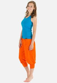Türkiissinine tank top, mis on kombineeritud lõtvade, erksate oranžide haremipükstega, millel on pahkluude mansetid, nööriga vöökoht ja küljetaskud.