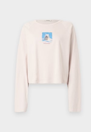 Roze cropped sweatshirt met lange mouwen, met een rechthoekige afbeelding van een hond tegen een blauwe lucht en de tekst "todeviler" eronder.