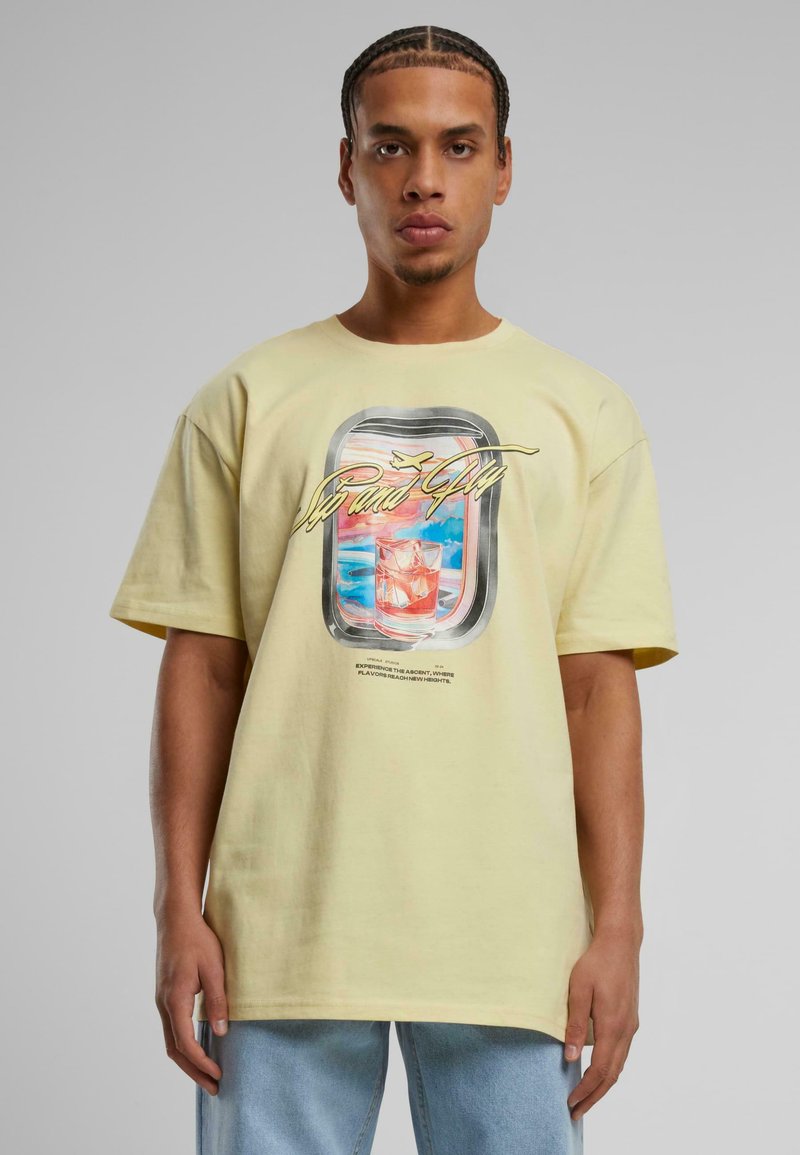 Geel katoenen T-shirt met een grafisch ontwerp van een drank en een wolken achtergrond. Losse pasvorm met korte mouwen en een ronde hals.