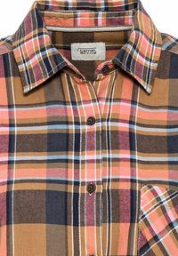 Chemise à carreaux à boutons avec des rayures marron, orange, rose, marine et blanche, avec un col plié et une poche poitrine.