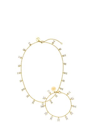 Goldkette und Armband-Set mit abwechselnden rechteckigen und quadratischen klaren Edelstein-Anhängern auf weißem Hintergrund.