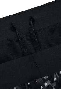 Gros plan d'une ceinture élastique noire avec deux cordons noirs et un tissu à motifs en dessous.