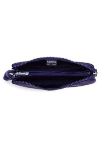 Cartera de nailon púrpura con cierre de cremallera, que cuenta con dos compartimentos y un suave acento de pom-pom en el tirador de la cremallera. Diseño ligero.