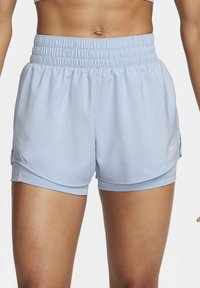 Gros plan sur un short de sport bleu clair avec une ceinture élastique porté par une personne, montrant le haut des cuisses et le bas-ventre.