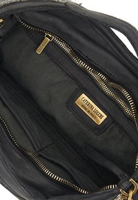 Interno di una borsa a tracolla in pelle nera con cerniere in tono oro, fodera in tessuto e un'etichetta con il marchio "CATERINA LUCCHI MADE IN ITALY."
