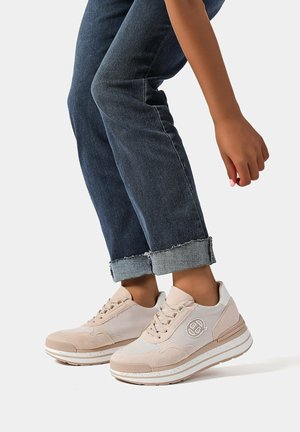 Scarpe sportive beige realizzate in materiali mesh e suede, con un accento bianco sul tallone e una suola texturizzata. Indossate con jeans scuri arrotolati.