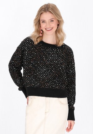 Maglione nero lavorato a maglia con una vestibilità ampia, motivo testurizzato e polsini a coste. Accentuato con fili neutri e metallici per un interesse visivo.