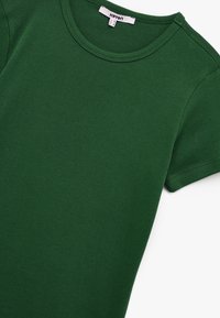 Camiseta de algodón verde con cuello redondo y mangas cortas. La tela es suave y uniforme en textura, sin patrones o acentos visibles.