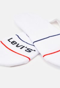 Weiße Baumwollsocken mit roten und marineblauen Streifen. Mit einem auffälligen schwarzen Logo, das "Levi's" auf der Seite liest. Weicher, dehnbarer Stoff.