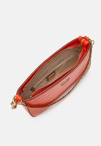 Mała czerwona torebka o fakturze krokodylej z złotym łańcuchem, z zamykanymi komorami i beżowym wnętrzem z logo.