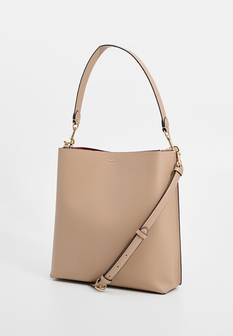 Sac fourre-tout en cuir beige avec une forme structurée, une poignée supérieure unique et une bandoulière réglable. Il présente une texture lisse et des accents en matériel doré.