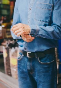 Denim särk eesolevate taskutega, kantud siniste teksade ja musta vööga. Käed, millel on tätoveeringud, kohandavad särgi varrukaid.