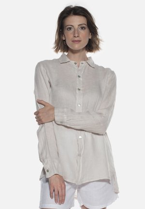 Chemise en lin beige clair avec un devant à boutons, des manches longues et un ourlet légèrement arrondi. Comprend des boutons semblables à des perles et un col.