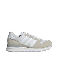 Baskets basses Adidas blanches et beige clair avec empeigne en mesh et daim, fermeture à lacets et semelle amortissante.