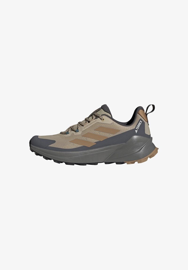 Beige og brun Adidas Terrex vandresko med sorte detaljer, tyk sål og trækstrop på hælen, vist fra siden.