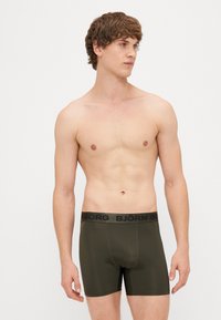 Oliivirohelised bokserid musta vööga, millel on "BJÖRN BORG" bränding, valmistatud siledast ja venivast kangast mugavuse tagamiseks.