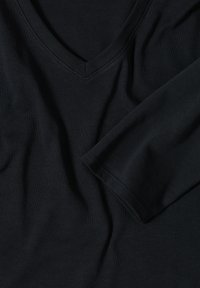 Chemise noire à manches longues et décolleté en V, fabriquée dans un tissu doux et lisse, avec une silhouette ajustée et des ourlets soigneusement cousus.