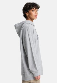 Γκρι φούτερ με κουκούλα σε άνετη εφαρμογή, με ριμπ μανσέτες και τελείωμα. Διαθέτει κεντημένο λογότυπο στο στήθος. Μαλακό ύφασμα από βαμβακερό μείγμα.