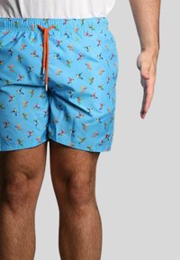Pantaloni da bagno blu con un motivo ripetuto di uccelli colorati. Presentano una vita elastica con un laccio arancione. Il materiale sembra leggero.