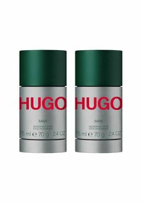 Två deodorantstift med gröna lock och silverfärgade baser. Etiketterna inkluderar röd text och detaljer: "HUGO MAN," "75 ml," "70 g," och "24 OZ."