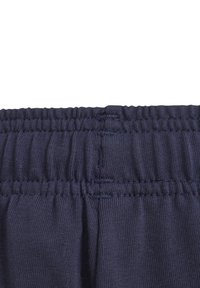 Navy blue waistband of elastic fabric, featuring horizontal ribbing texture and gathering details, designed for comfort and flexibility.
