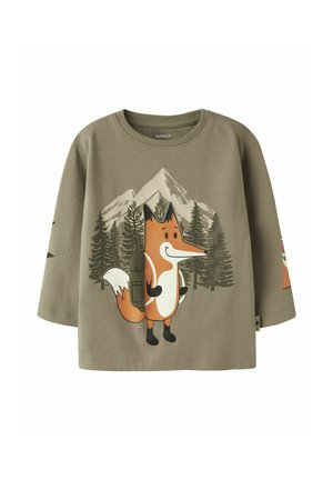 Chemise verte à manches longues pour enfants avec un renard de dessin animé portant un sac à dos, debout devant des pins et des montagnes enneigées.