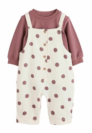 Peto de bebé con tela blanca y grandes lunares malva, con botones en la parte delantera y combinado con una camiseta de manga larga malva.