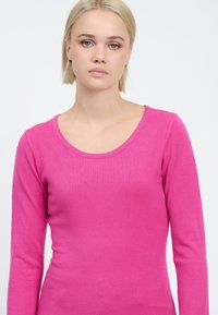 Maglione aderente a maniche lunghe di un rosa vivace, con scollatura rotonda e una consistenza morbida, adatto per un look casual.