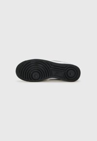 Black rubber sneaker sole with circular tread patterns, featuring a flat design and textured surface for grip.