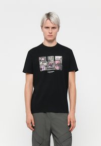 Sort bomulds t-shirt med et grafisk collage af billeder på forsiden i pink og grå nuancer. Rund halsudskæring og korte ærmer.