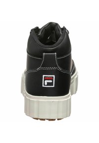 Musta nahkakengät, joissa on pehmustettu kaulus, valkoinen ommel, paksu kumipohja ja takana logo-tägi punaisen, valkoisen ja sinisen korostuksen kanssa.