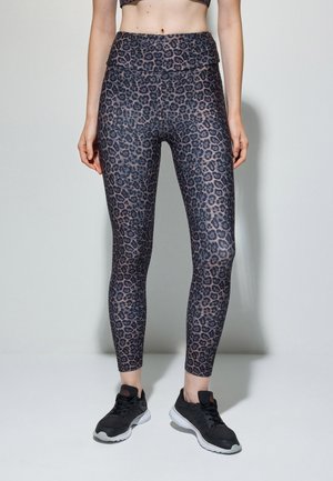 Leggings realizzati in tessuto elasticizzato con un motivo a stampa leopardata nero e grigio, con vita alta e abbinati a scarpe sportive nere.