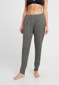 Schwarz-weiße gemusterte Hose mit einem elastischen Bund, schmal zulaufenden Beinen und einer weichen Stofftextur. Keine sichtbaren Beschläge oder Akzente.