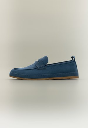 Ein einzelner marineblauer Loafer mit einer braunen Sohle, mit einem genähten Riemendetail und einem Zuglasche an der Ferse, auf neutralem Hintergrund.