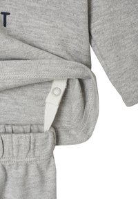 Gray cotton outfit with ribbed cuffs, an adjustable white strap with snap closure, and a soft texture. No visible patterns or graphics.