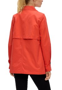 Rode, lichtgewicht jas met een achterklep, knoopmanchetten en een kraag, ontworpen voor een ontspannen pasvorm. Gladde textuur en minimale styling.