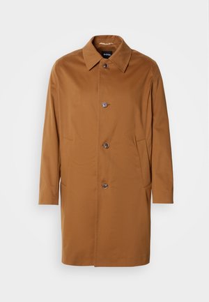 Barna trench kabát gallérral, két oldalsó zsebbel és három elülső gombbal. Simított anyagból készült, egyenes szabású kialakítással.