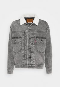 Grå denimjacka med en vit faux shearling-krage, två bröstfickor och en knappstängning med kontrasterande sömmar.