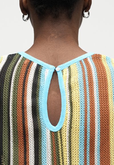 Κοντινή λήψη του πάνω μέρους της πλάτης ενός ατόμου που φοράει πολύχρωμο πλεκτό τοπ με ρίγες, κούμπωμα κλειδαρότρυπας με μπλε περίγραμμα και ασημένια σκουλαρίκια σε σχήμα κρίκου.